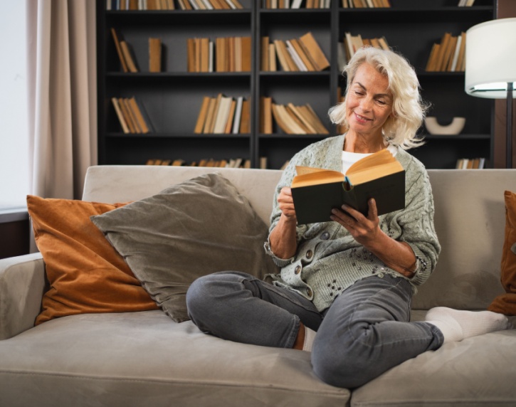 Smiling lady sitting on a sofa reading a book